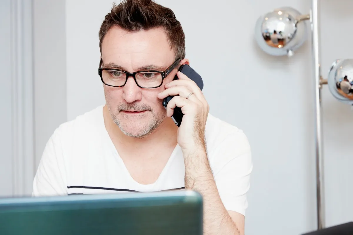 Mand med briller taler i telefon ved sit hjemmekontor